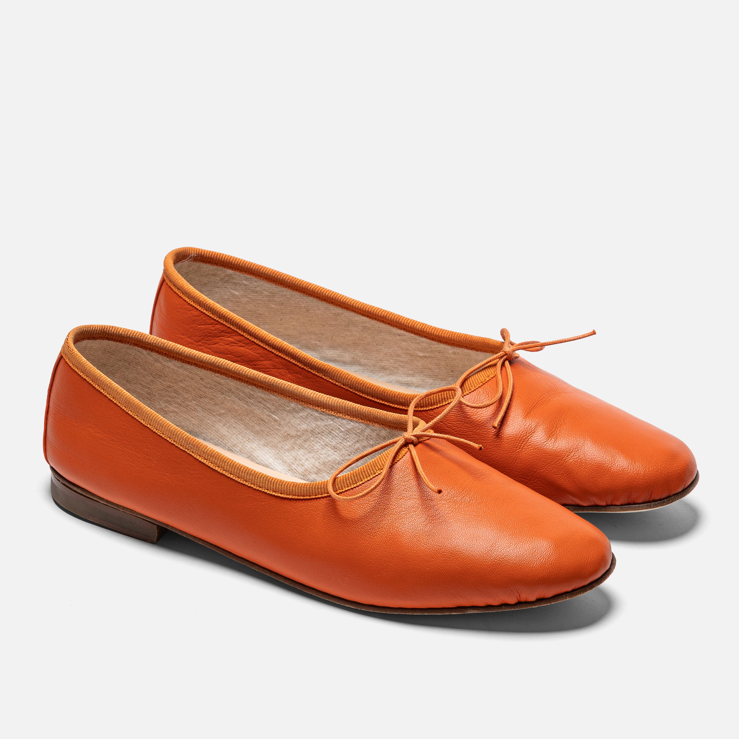 Pair of orange leather shoes with laces on a white background