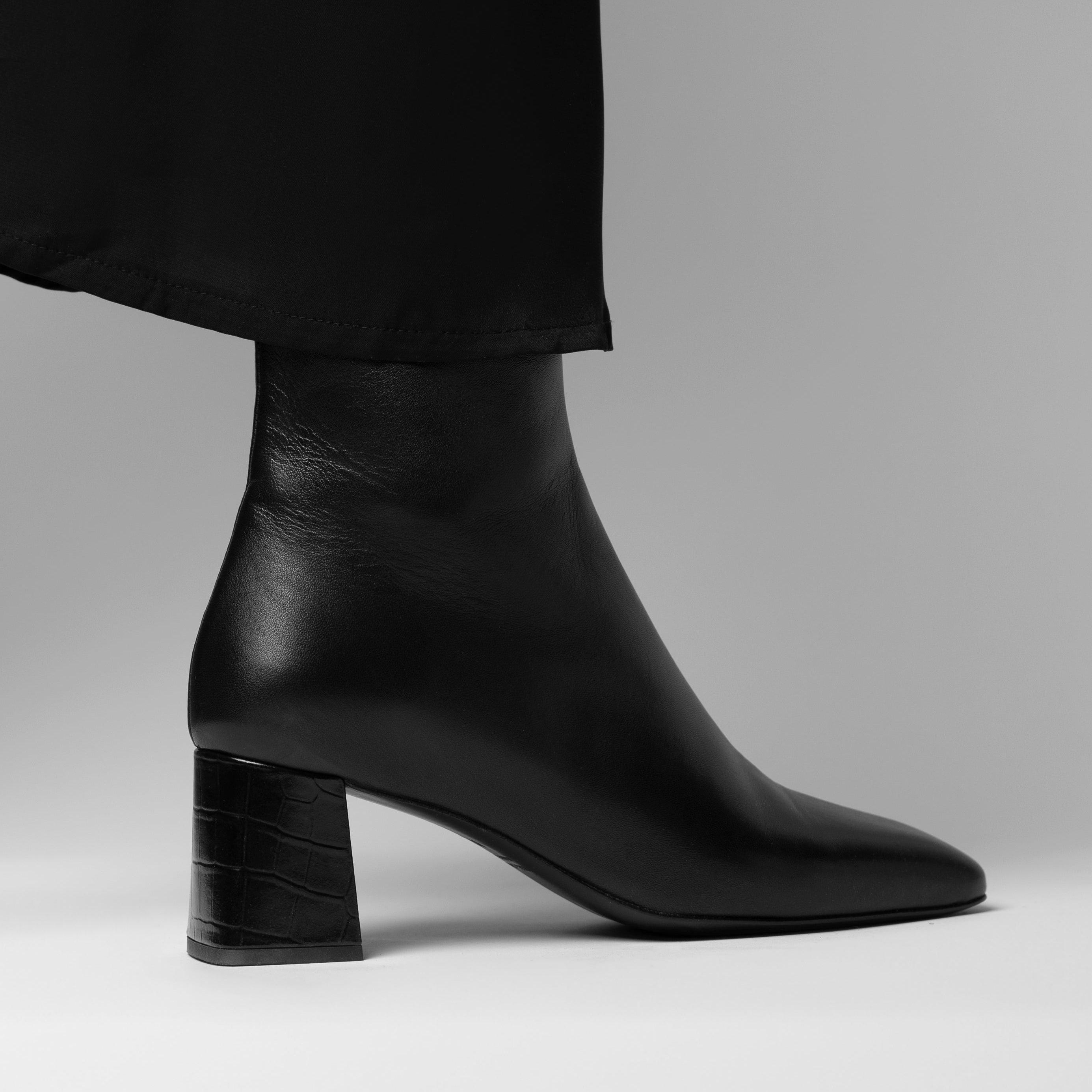 Black leather ankle boot on a gray background