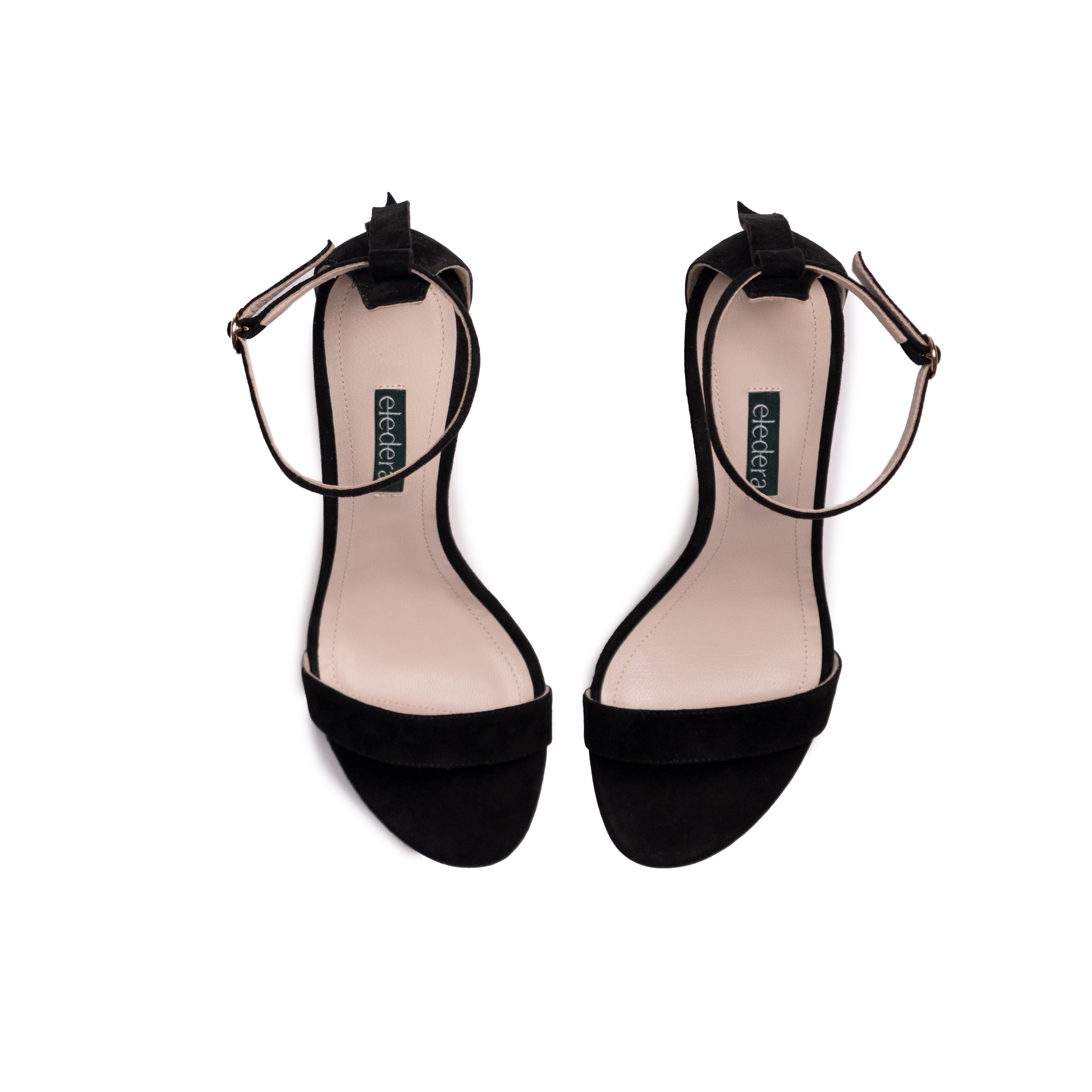 The Eledera Tacco in smooth black suede leather, 7cm heel, adjustable strap with golden buckle and embellished tassel on the back.