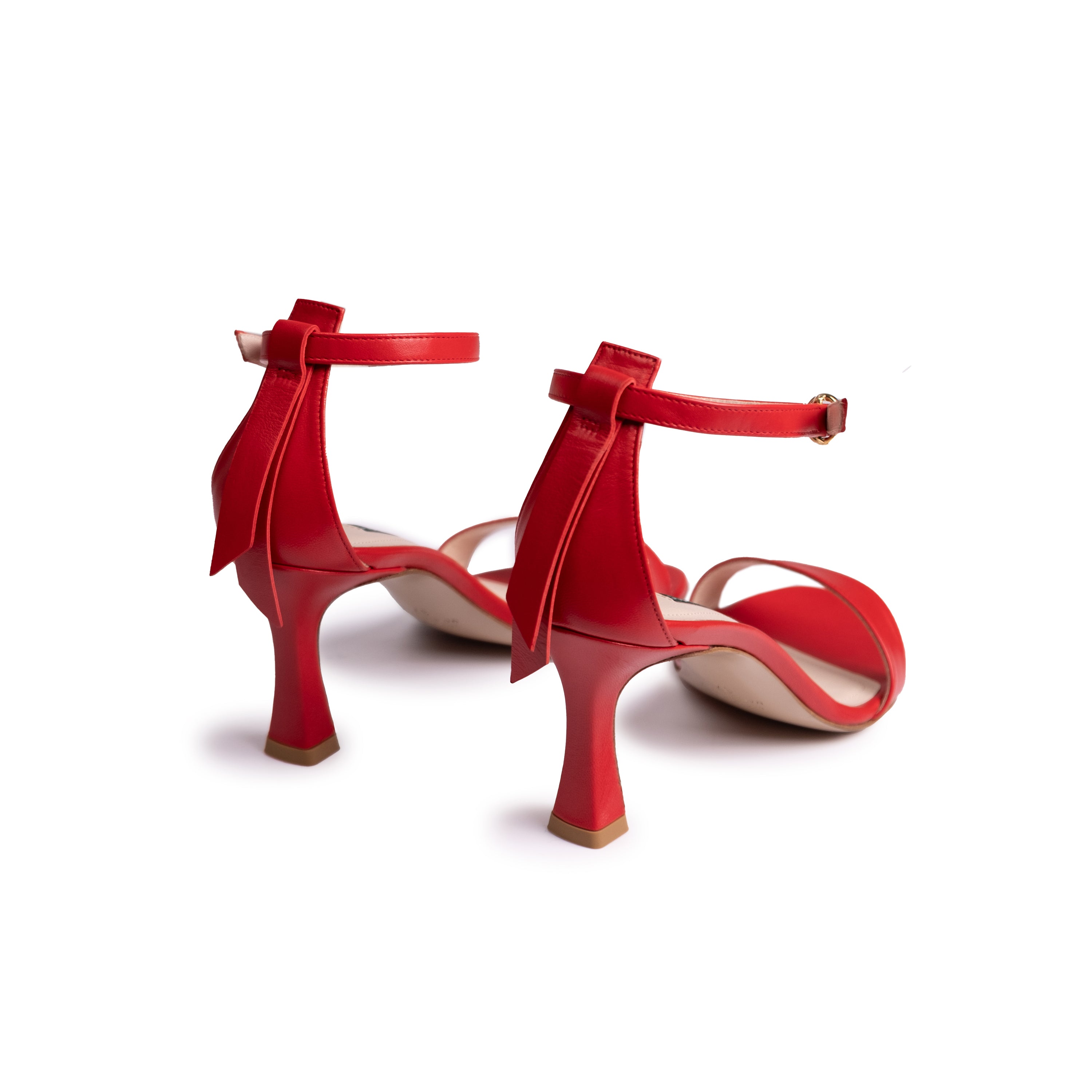 The Eledera Tacco in red nappa leather, 7cm heel, adjustable strap with golden buckle and embellished tassel on the back.