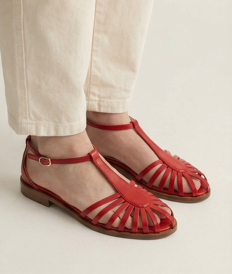 Red sandals with cut-out design worn by a person on a light background