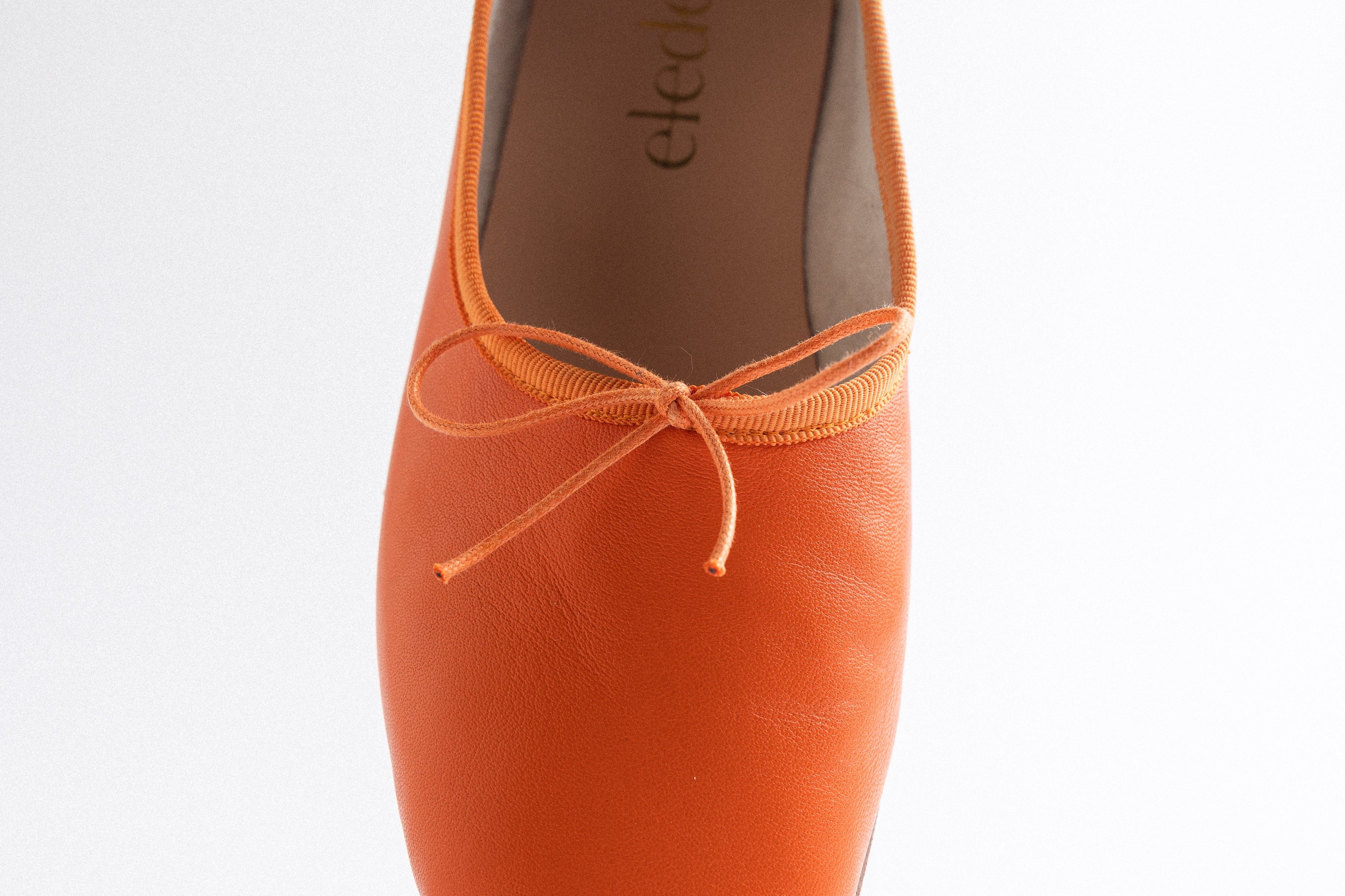 Orange ballet shoe with a white background