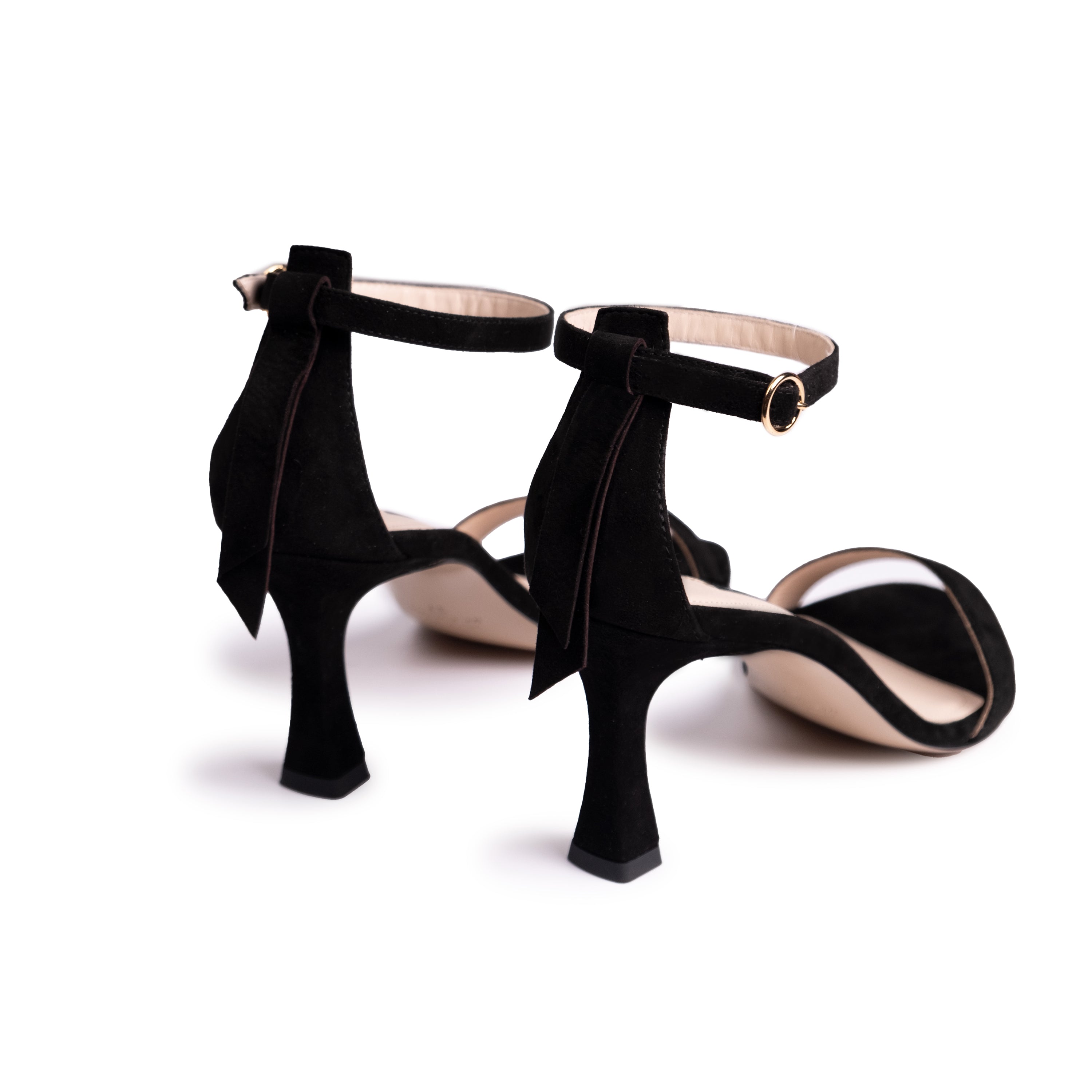 The Eledera Tacco in smooth black suede leather, 7cm heel, adjustable strap with golden buckle and embellished tassel on the back. 